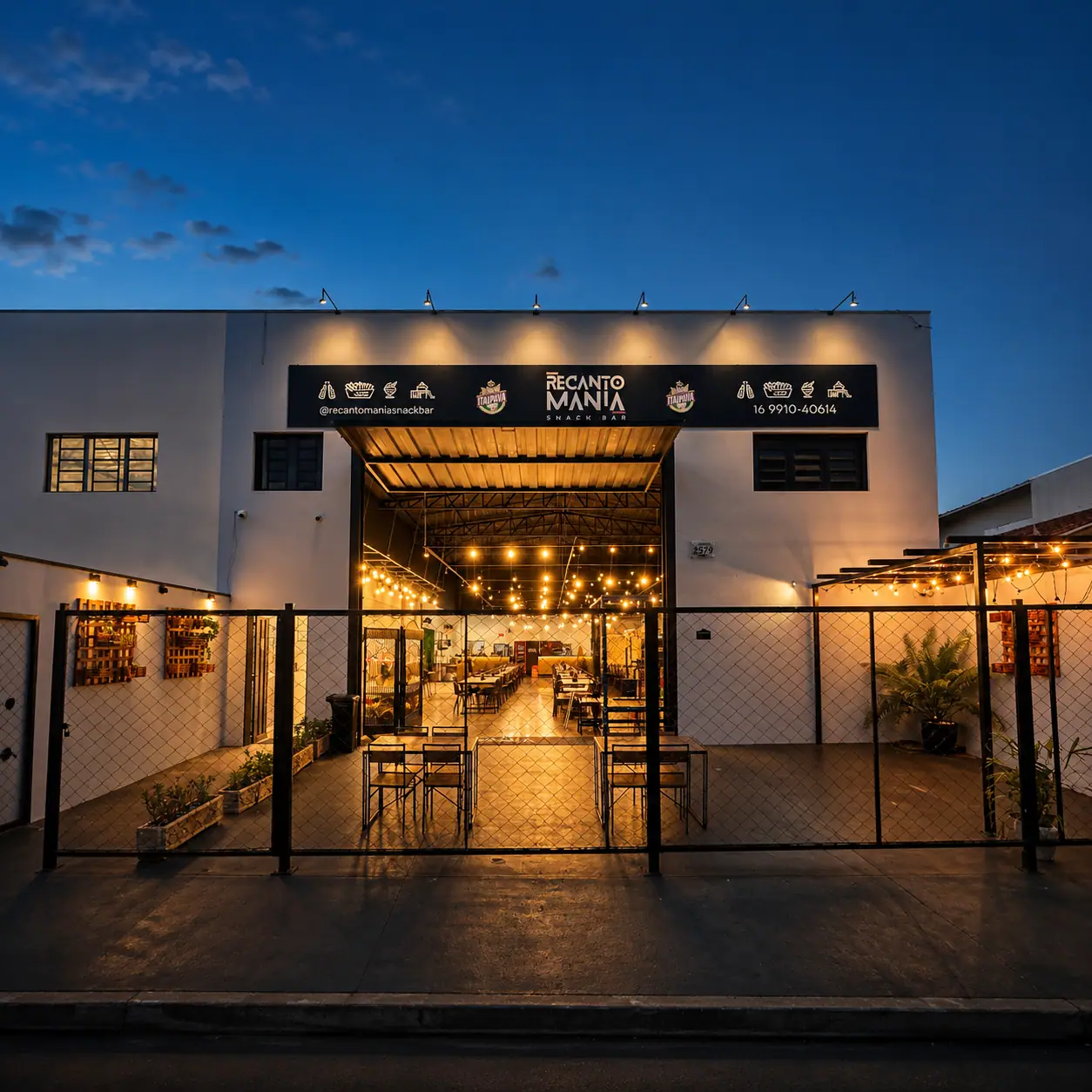 Fachada do Recanto Mania Snack Bar iluminada à noite